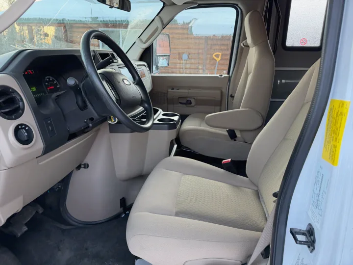 Clean, spacious beige interior of an RV rental van, showing driver and passenger seats, dashboard, and steering wheel.. Forester Forester Motorhome 2020