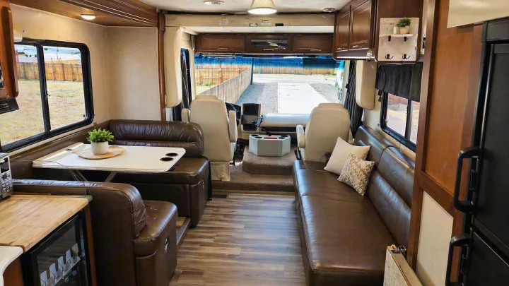 Spacious RV rental interior: A cozy living space with leather sofas, dining area, and front cockpit visible.. Coachmen Pursuit 2014