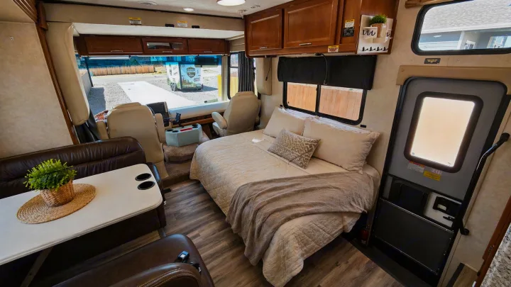 Explore this clean & spacious RV rental interior, featuring a comfy bed, dining area, and driver's cabin for your next trip.. Coachmen Pursuit 2014