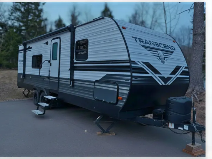 Spacious Transcend travel trailer RV rental, white with black & gray accents, parked on asphalt with steps deployed. Ready for adventure.. Grand Design Transcend 2020