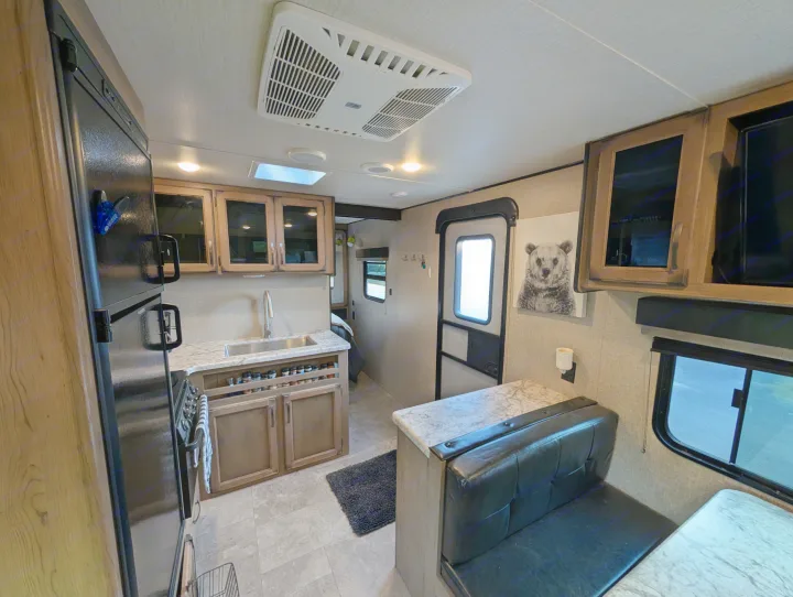 Spacious RV rental interior featuring a functional kitchen with fridge, sink, stove, and a cozy dining booth.. Grand Design Transcend 2020