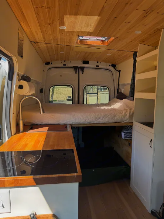 Cozy rv rental interior: wood ceiling, bed, kitchenette w/ induction cooktop & sink. Perfect for van life adventures.. Ford Transit 250 AWD 2022