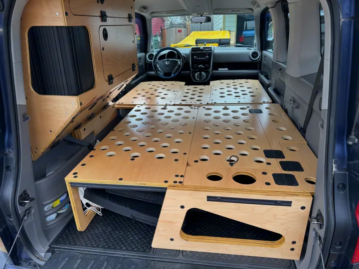 RV rental ready: Honda Element interior with custom plywood camper bed and side storage units, optimized for camping.. Honda Element 2010