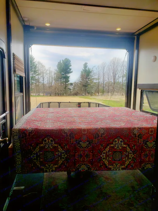 Enjoy nature from your RV rental! Open rear door reveals a unique rug-covered bed & a view of trees/field.. Grand Design Momentum 2017