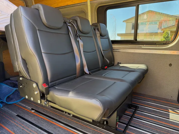 RV rental: Flexible three-person black bench seat with individual seatbelts on adjustable floor rails in a spacious van.. Mercedes-Benz Sprinter 2025
