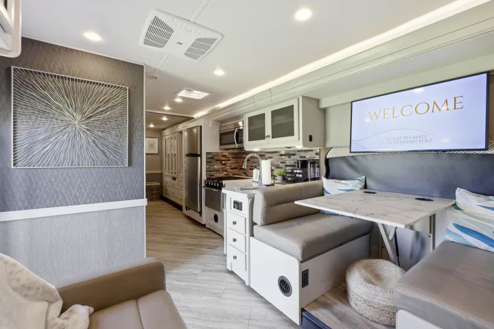 Experience this modern RV rental interior featuring a bright kitchen, dining booth with TV, and comfortable living area.. Fleetwood Fortis 2021