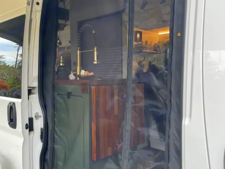 Modern rv rental interior, featuring a kitchen with gold faucet & wood counter, viewed through a clear bug screen.. Dodge Other 2023