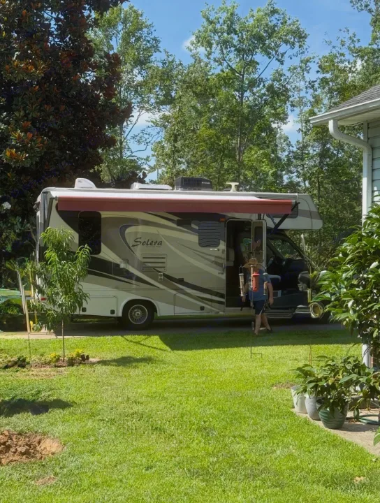RV rental motorhome parked on a sunny day, with a person near the open door and a green landscape.. Forest River Solera 24R 2014