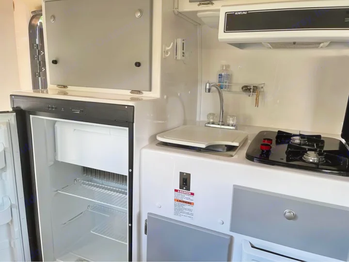 Explore this compact rv rental kitchen featuring an open refrigerator, sink, and two-burner stove. Ready for your travels!. Casita Casita Trailer 2020