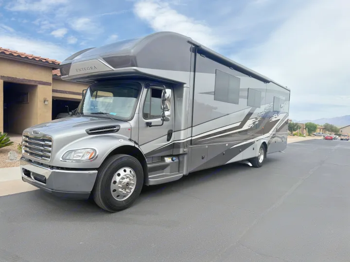 Sleek grey Entegra Accolade motorhome, ideal for your next RV rental adventure, parked at home under a cloudy sky.. Entegra Coach Accolade 2025