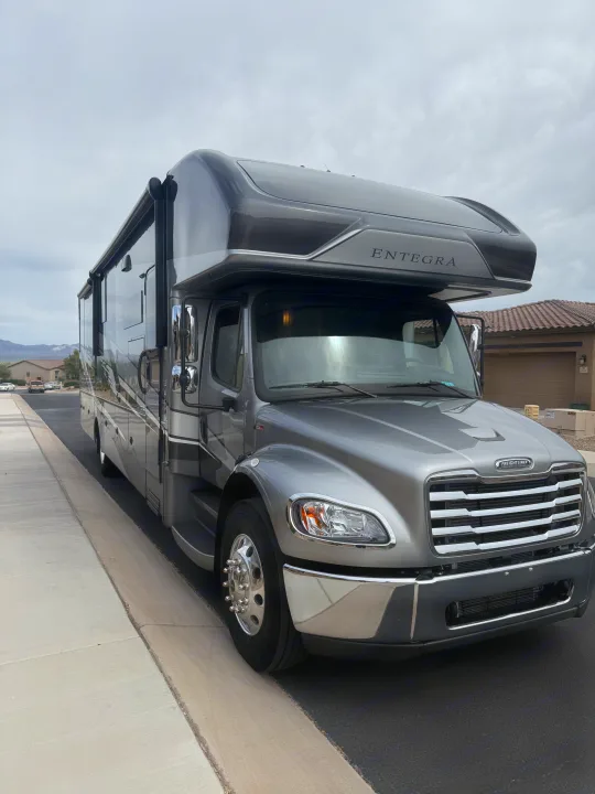 This large, grey Entegra Freightliner motorhome is ready for your next rv rental adventure, parked on a residential street.. Entegra Coach Accolade 2025