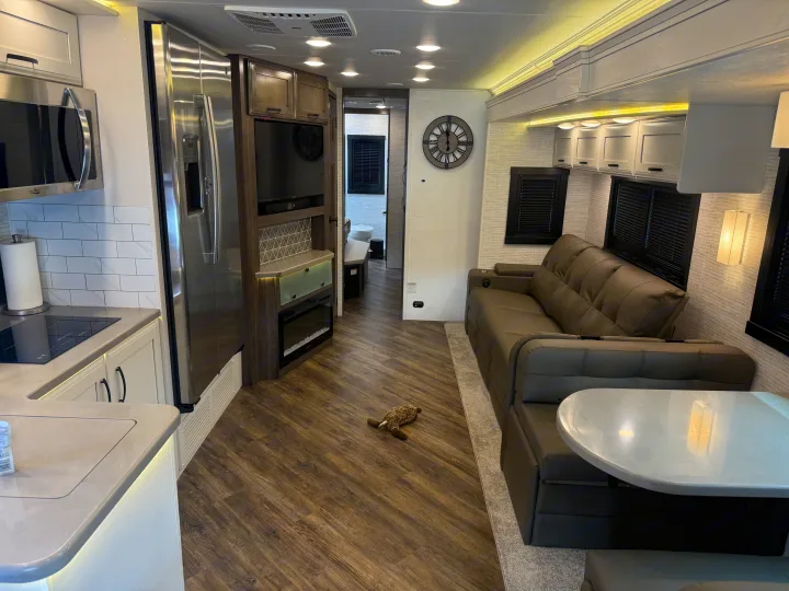 Explore this modern RV rental interior: full kitchen, entertainment center with fireplace, comfy lounge, & dining booth.. Entegra Coach Accolade 2025