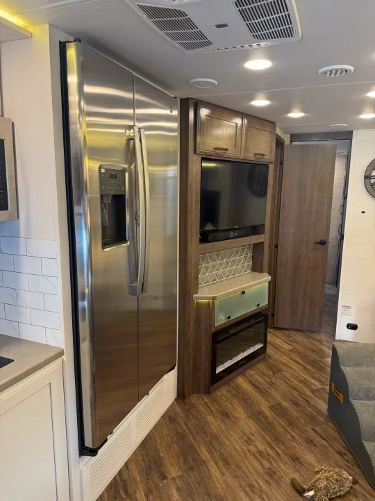 Step inside this modern rv rental. A stainless steel fridge, entertainment center with TV/fireplace, and cozy dog bed enhance the space.. Entegra Coach Accolade 2025