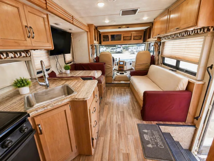 Spacious RV rental interior featuring a full kitchen, comfortable living area with couch, and a view into the cockpit.. Thor Motor Coach ACE 2018