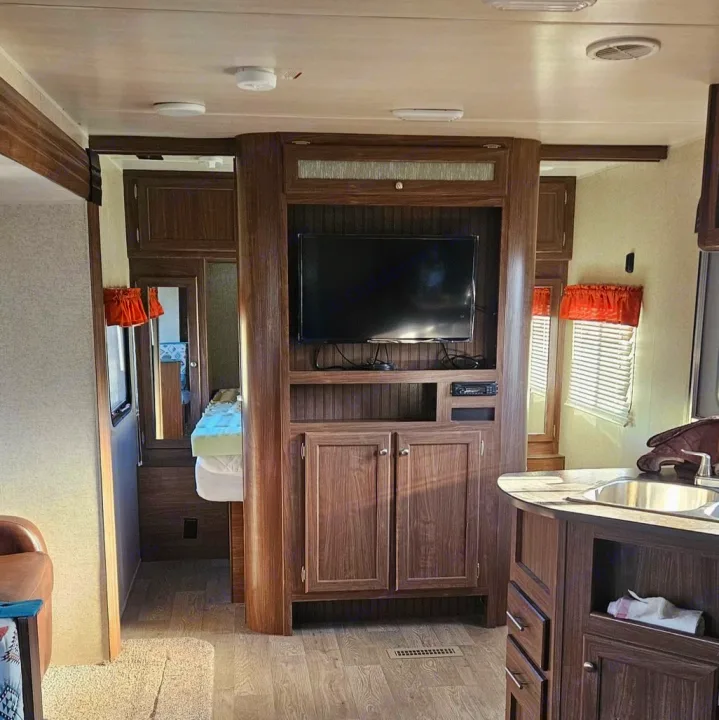 Explore this modern RV rental interior. It features a full kitchen, comfy living area, and a glimpse of the bedroom space.. Heartland RVs Prowler 2018