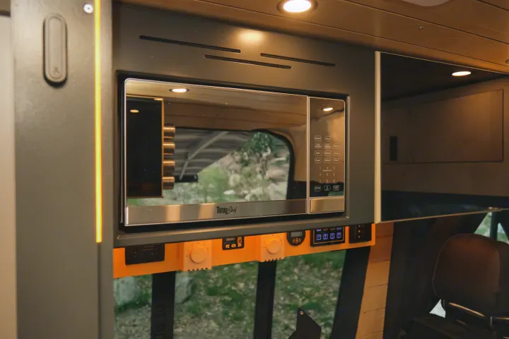 RV rental interior showcasing a built-in Total Chef microwave oven, control panel, and ambient LED lighting for convenient travel.. Mercedes Sprinter 2022