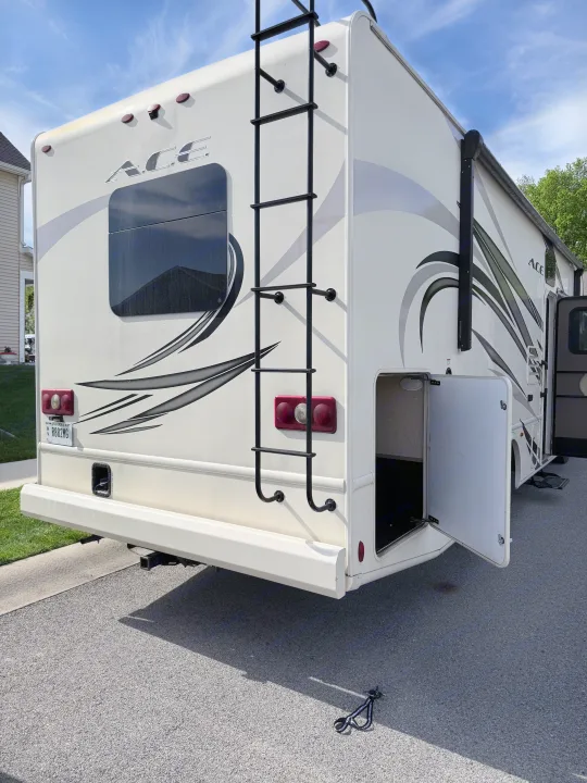 Detailed view of an ACE rv rental motorhome exterior: rear ladder, tail lights, and an open side storage bay.. Thor A.C.E. 2018