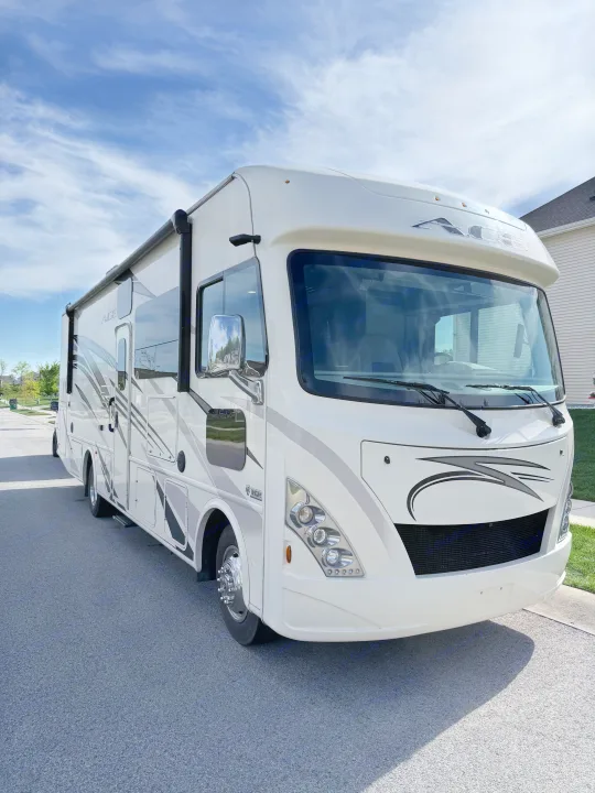 A white Thor ACE RV rental is parked on a street, featuring sleek grey graphics under a blue sky.. Thor A.C.E. 2018