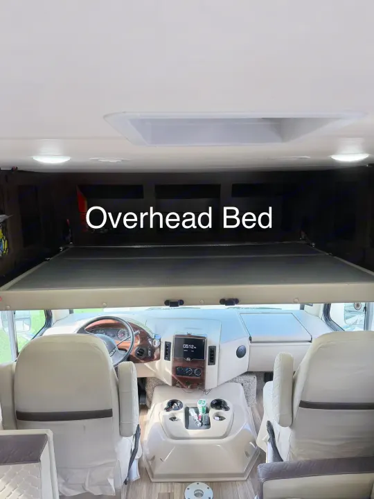 RV rental interior: driver's cockpit with captain chairs and a lowered overhead bed, providing extra sleeping space in this motorhome.. Thor A.C.E. 2018