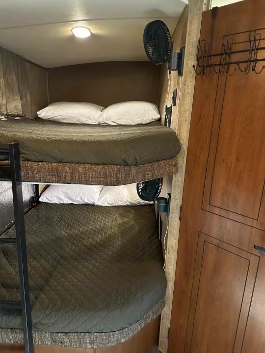 rv rental bunk beds feature cozy quilted bedding, individual fans for air circulation, and a door with a coat rack.. Outdoors RV Timber Ridge 2020