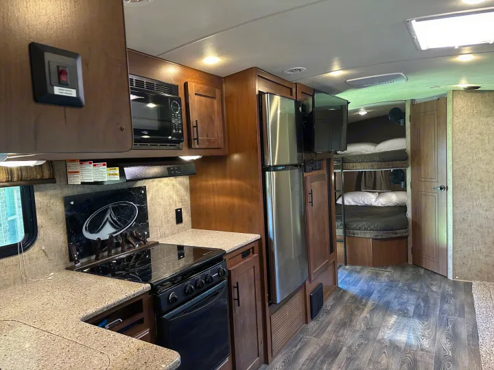 Spacious rv rental interior featuring a full kitchen with microwave, oven, fridge, and cozy bunk beds in the back.. Outdoors RV Timber Ridge 2020