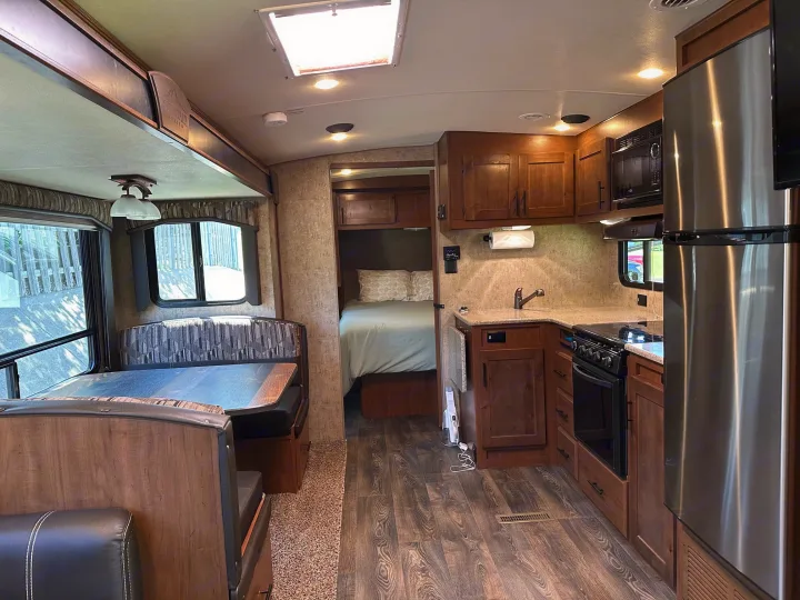 Spacious rv rental interior featuring a modern kitchen, dining booth, and cozy bedroom, ideal for travel adventures.. Outdoors RV Timber Ridge 2020