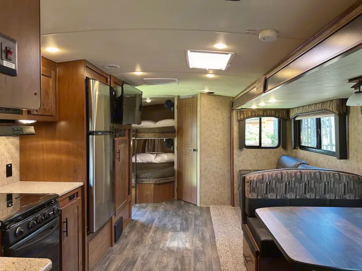 Bright RV rental interior with kitchen, bunk beds, and dinette. Enjoy comfortable living space on your next camper adventure.. Outdoors RV Timber Ridge 2020