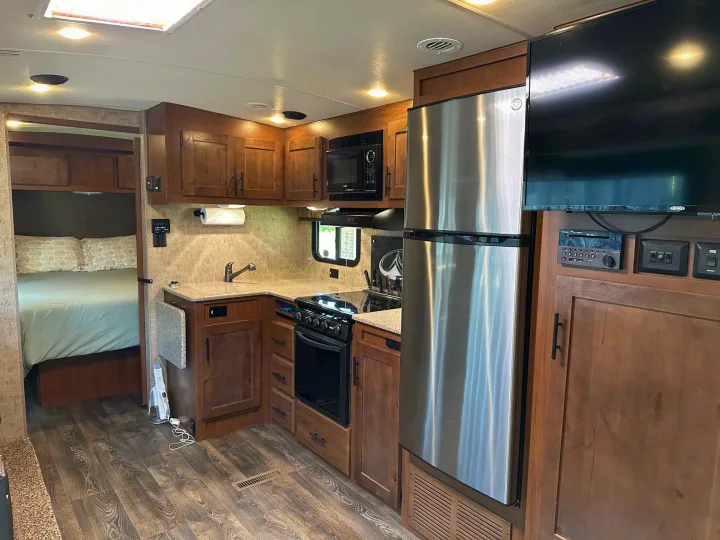Spacious RV rental kitchen with modern appliances and a peek into the bedroom. Ideal for your next adventure.. Outdoors RV Timber Ridge 2020