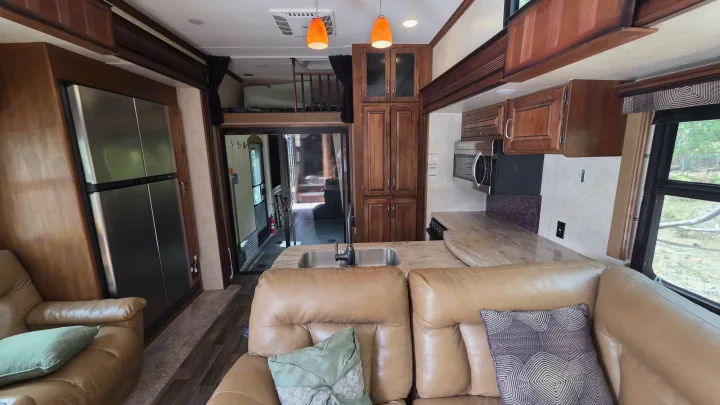 RV rental interior: modern kitchen, living area with leather sofas, fridge, and a cozy loft bed above.. Keystone RV Raptor Toy Hauler 2015