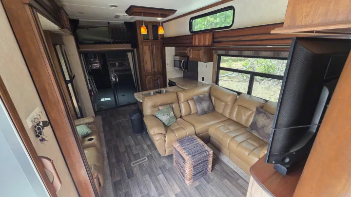 Spacious RV rental interior: a comfy leather sectional, full kitchen, and rear garage with a loft bed, ready for adventures.. Keystone RV Raptor Toy Hauler 2015
