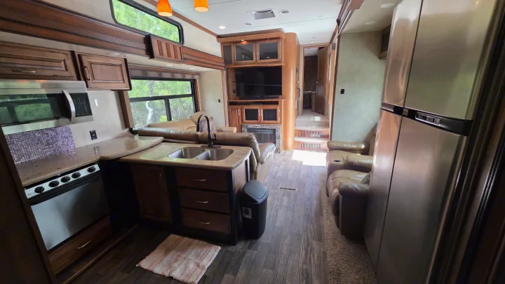 Inside this RV rental: a modern kitchen with stainless appliances, living room with fireplace, and plush seating.. Keystone RV Raptor Toy Hauler 2015