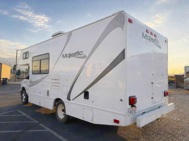 Experience comfort with this Majestic RV rental. A white motorhome with gray accents, parked outdoors with mountains in the distance.. Thor Majestic 2013
