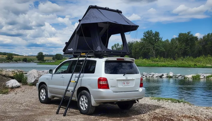 Silver SUV with rooftop tent by a river; an RV rental alternative for adventure and car camping.. Toyota Highlander 2005