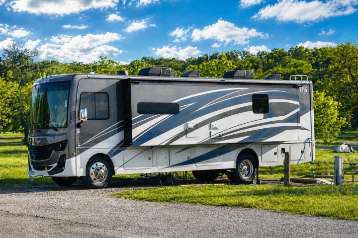 A modern grey and white rv rental motorhome is parked at a sunny campsite, ready for travel and outdoor adventures.. Fleetwood Fortis 2021