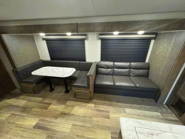 Explore comfort in this modern RV rental interior, featuring a U-shaped dinette with a table and a plush sofa.. KZ Connect SE 2021