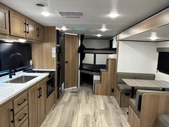 Spacious RV rental interior with full kitchen, bunk beds, and dining area, perfect for family adventures on the road.. Keystone RV Coleman Light 2025