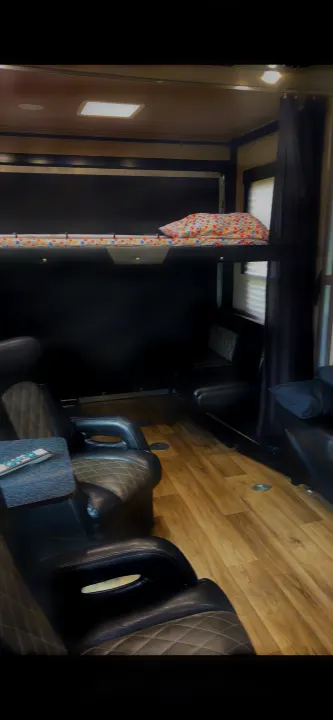 RV rental interior: Features a bunk bed, black and grey recliners, additional seating, and light wood-look flooring.. Genesis Supreme Rv Genesis Supreme 2019