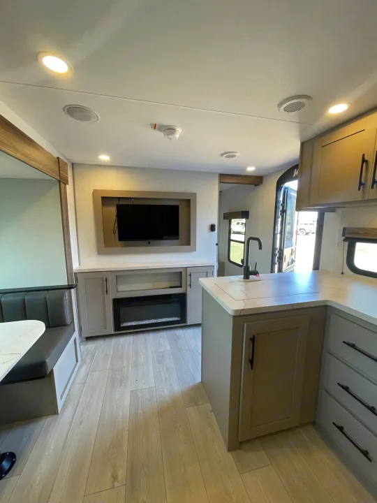 Bright, modern RV rental interior showing a kitchen counter with sink, entertainment center with TV, fireplace, and dining nook.. KZ Connect 241BHKSE 2026