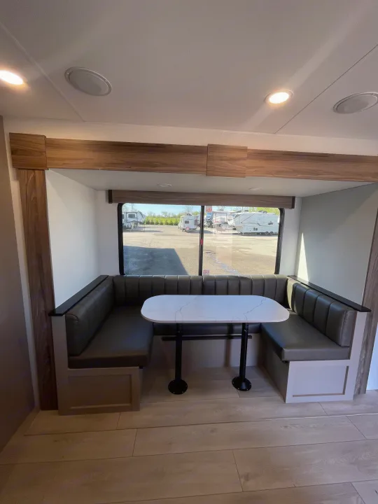 Cozy RV rental dinette featuring modern U-shaped seating, a white marble-look table, and a bright window view.. KZ Connect 241BHKSE 2026