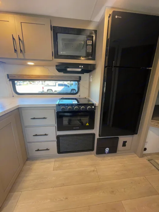 Modern rv rental kitchen featuring GE Profile fridge, InVision microwave/hood, Greystone stove, light cabinets, and flooring.. KZ Connect 241BHKSE 2026