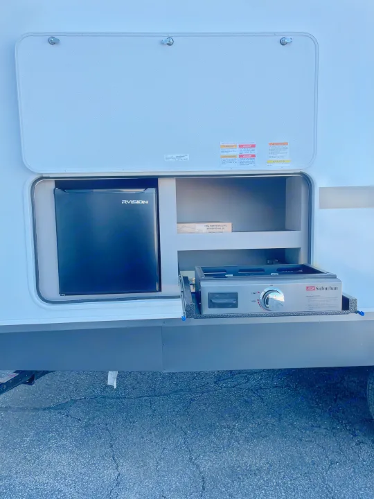 An RV rental's open outdoor kitchen with a mini-fridge, Suburban gas grill/cooktop, and griddle, perfect for camping.. KZ Connect 241BHKSE 2026