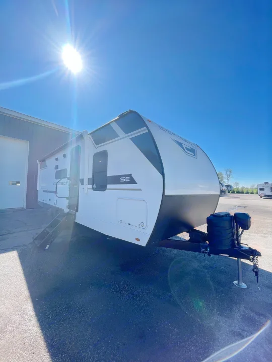 This new white Connect SE travel trailer, ready for rv rental, shines brightly in the sun with its steps extended.. KZ Connect 241BHKSE 2026