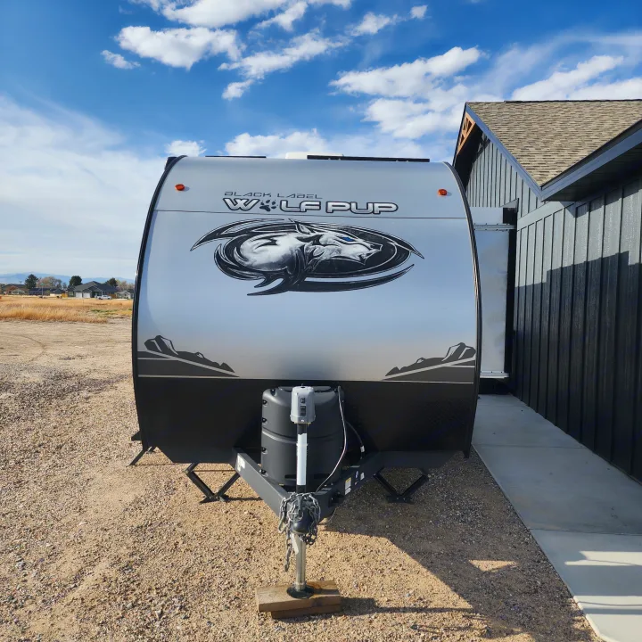 Front of a sleek Wolf Pup travel trailer, featuring a wolf logo. Perfect for your next RV rental journey!. Forest River Cherokee Wolf Pup Black Label 2022