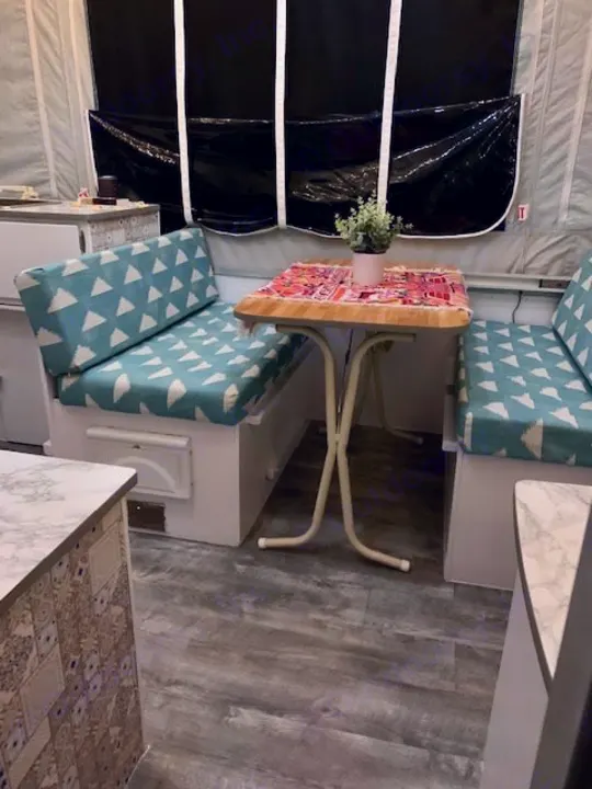 This RV rental features a compact, updated dinette with stylish cushions & a plant, perfect for meals on the road.. Viking Pop Up 2004