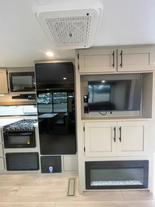 RV rental interior: modern kitchen with fridge/oven, entertainment center with TV, fireplace, and ceiling AC for comfort.. KZ CONNECT 271BHSE 2026