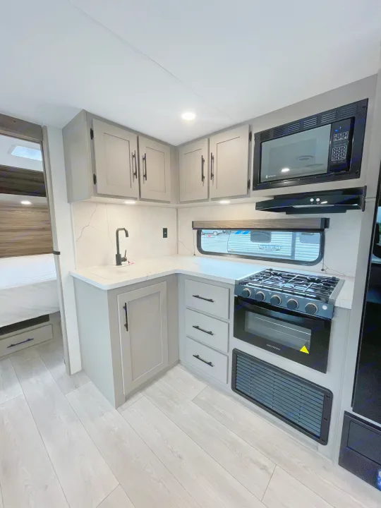 Explore this RV rental's sleek kitchen, featuring modern gray cabinets, marbled counters, full appliances, and bright lighting.. KZ CONNECT 271BHSE 2026
