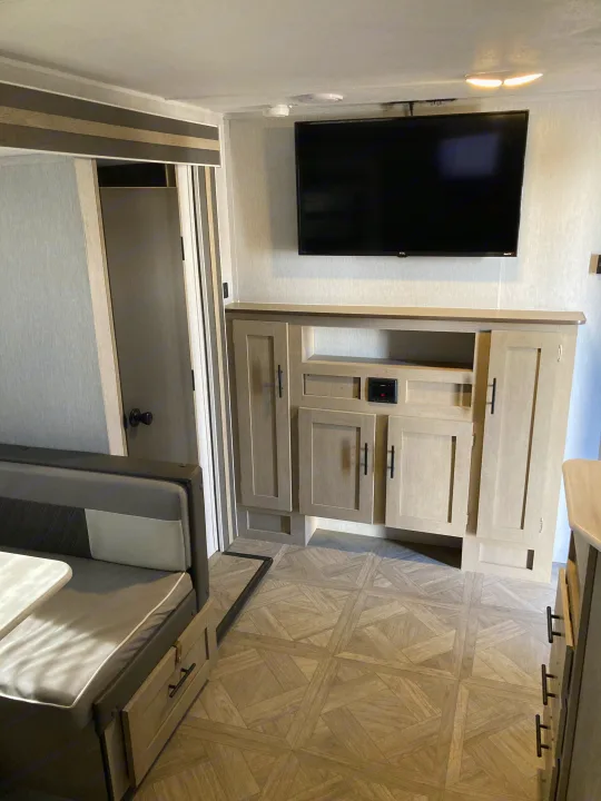 RV rental interior: A modern living space with a wall-mounted TV, light-toned cabinetry, a dinette, and geometric patterned flooring.. Forest River Salem Cruise Lite 2023