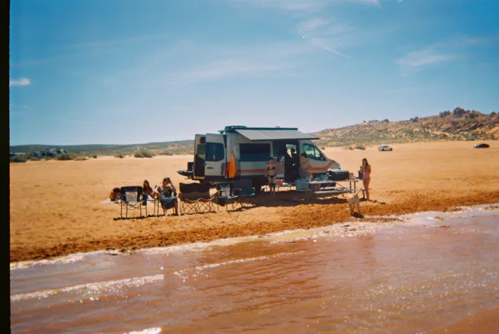 An RV rental offers the perfect setup for friends and a dog enjoying a sunny day of beach camping by the water.. Mercedes Sprinter 2025