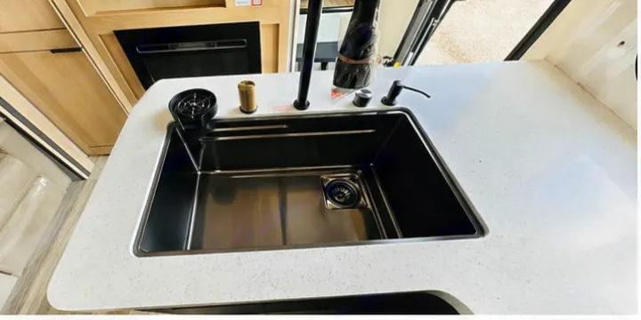 Modern RV rental kitchen with a sleek black sink, glass rinser, and bright countertop. Essential amenities for your journey.. Cruiser RV 32BH 2025