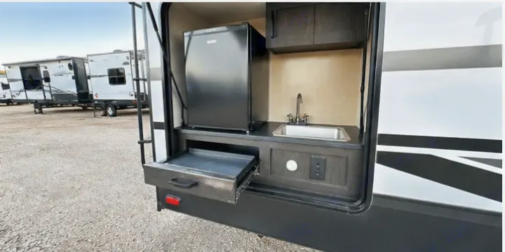 This rv rental offers a fully equipped outdoor kitchen with a fridge, sink, and pull-out griddle for convenient cooking.. Cruiser RV 32BH 2025